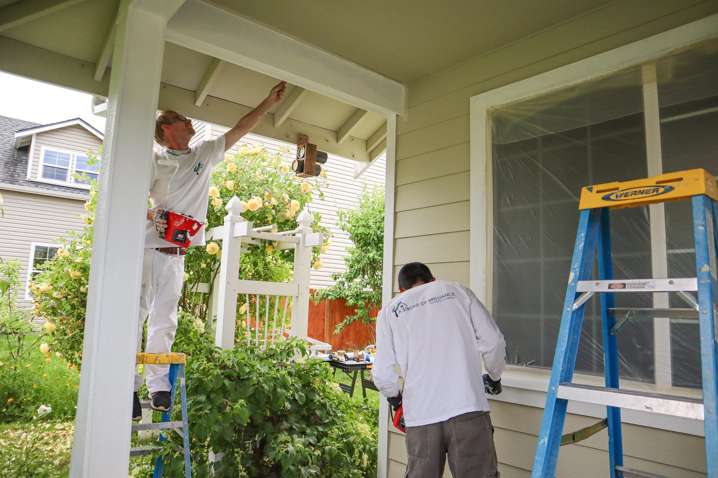 A Stroke of Brilliance painters cutting in a porch ceiling on a Marysville home