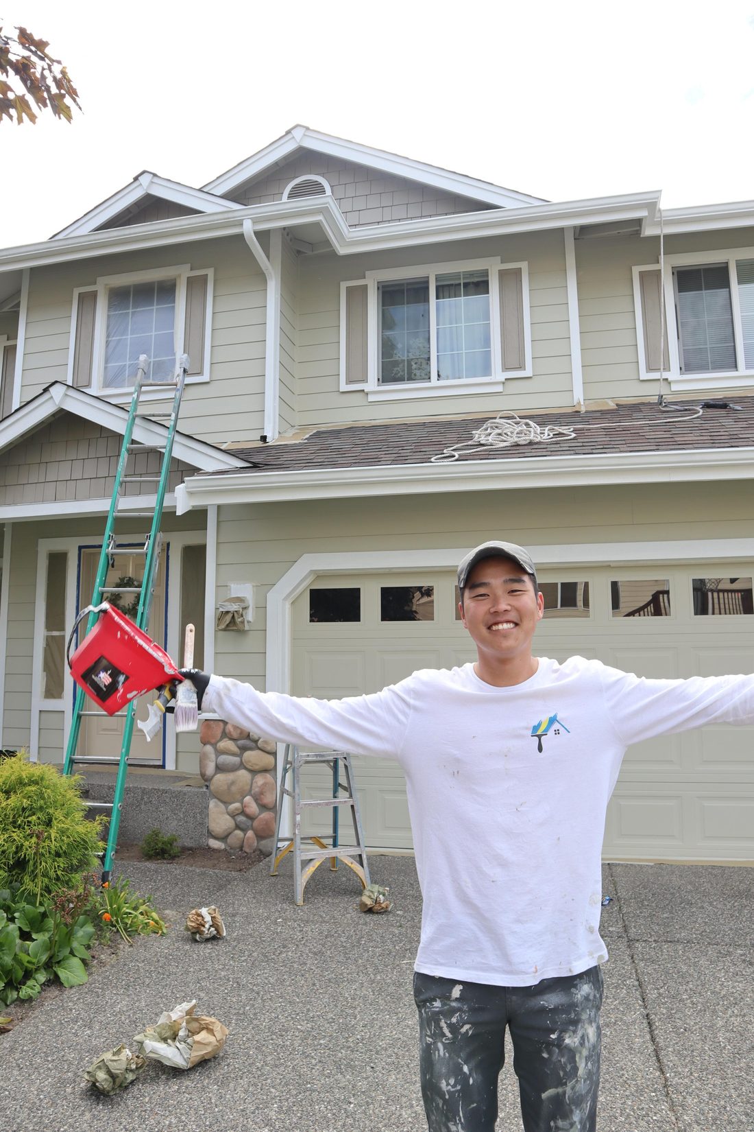 A Stroke of Brilliance painter in front of a freshly repainted Marysville two-story home