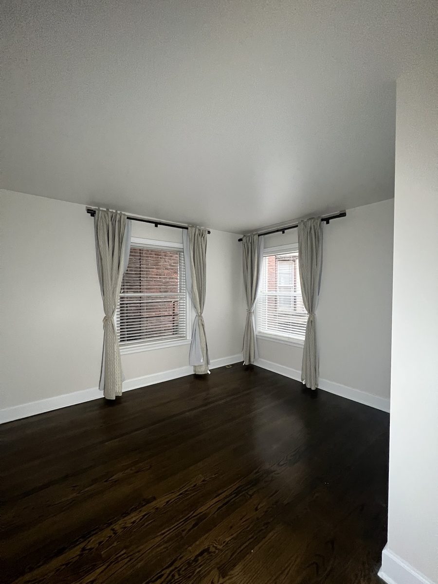 Freshly painted interior room with crisp white walls over dark hardwood