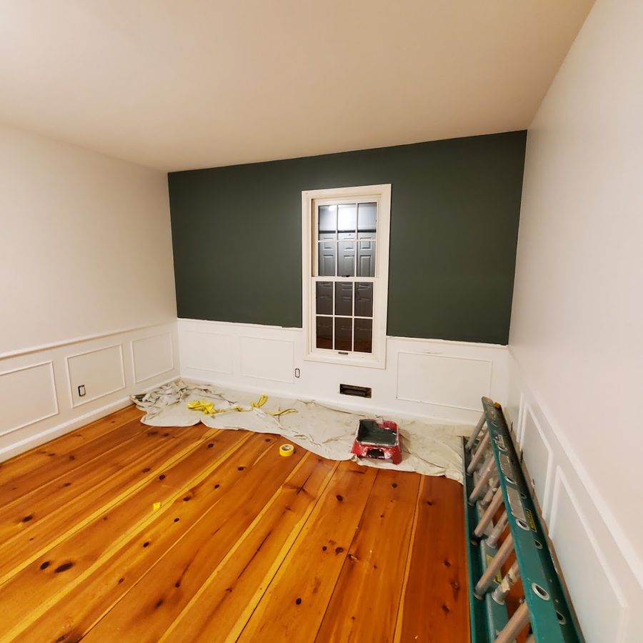 Deep green accent wall over white wainscoting, mid-project with drop cloths down